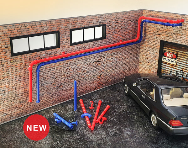 A diorama setup featuring red and blue plastic pipes of various lengths, designed for scale modeling and garage display.