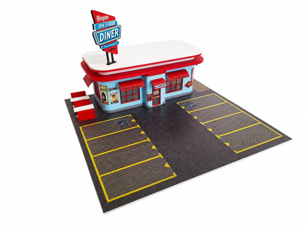 A miniature model of a retro 1950s diner building with a red and white rounded roof, blue walls, and a red-and-white sign, shown with a black parking lot and yellow painted lines on a white background.