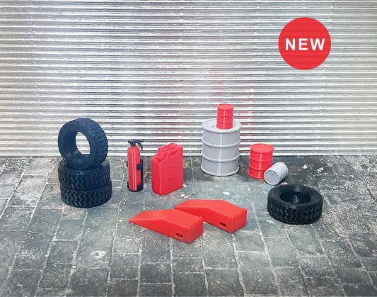 A set of small garage equipment models in 1:24 scale, including tires, stop ramps, a fire extinguisher, an oxygen bottle, a petrol tube, and barrels, displayed on a textured surface with a 'New' sticker on the top left.