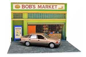 Model of a store front with a car parked in front, labeled 'Bob's Market'.