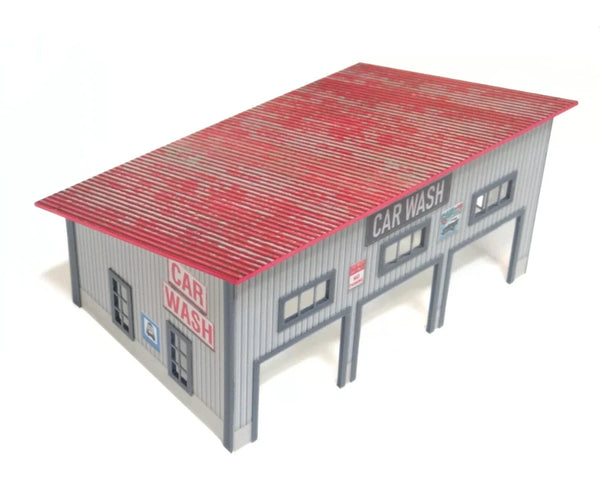 Model of a car wash building with red roof and gray walls on a white background