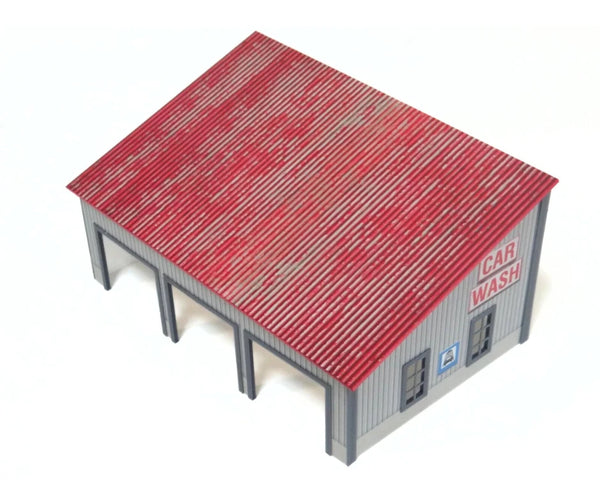 Model of a car wash building with a red roof on a white background from behind.