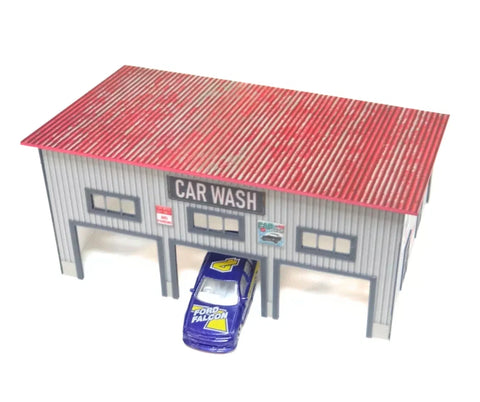 Model car wash with a red roof and a blue model car in front on a white background