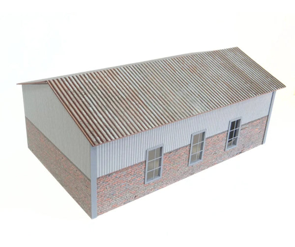 Model of a building with a corrugated metal roof and brick walls on a white background