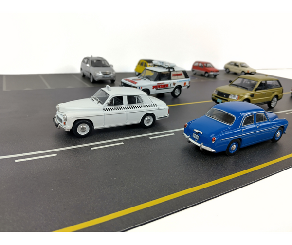 Model cars on a miniature road with white lines