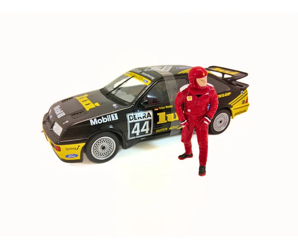 Model car with racing livery and a person in a red racing suit standing next to it on a white background