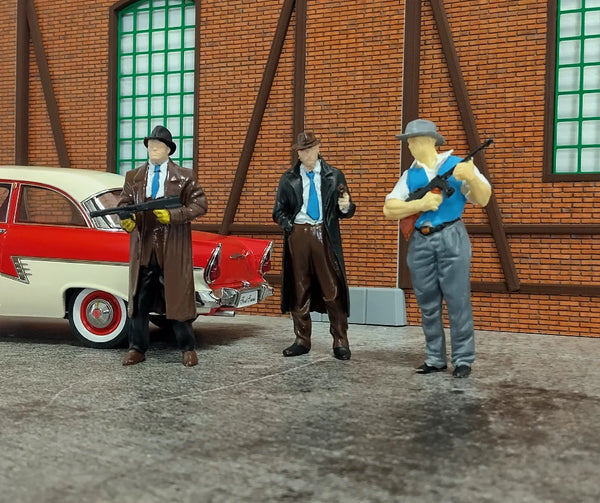 Three action figures in front of a red and white car with a brick building background